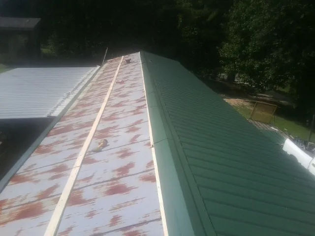 Old rusted panels beside newly installed green metal roofing — Wind Damage Roof Repair by Roofing Brothers in Brilliant