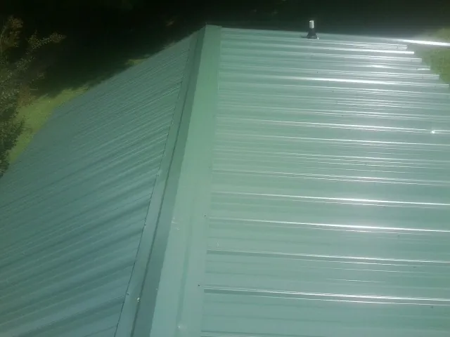 New green metal panels meeting at the ridge of a roof — Flat Roof Repair work by our crew in Brilliant