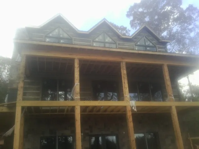 Dormers and porch framing on a large log home under construction — Roof Coating work by our crew in Brilliant
