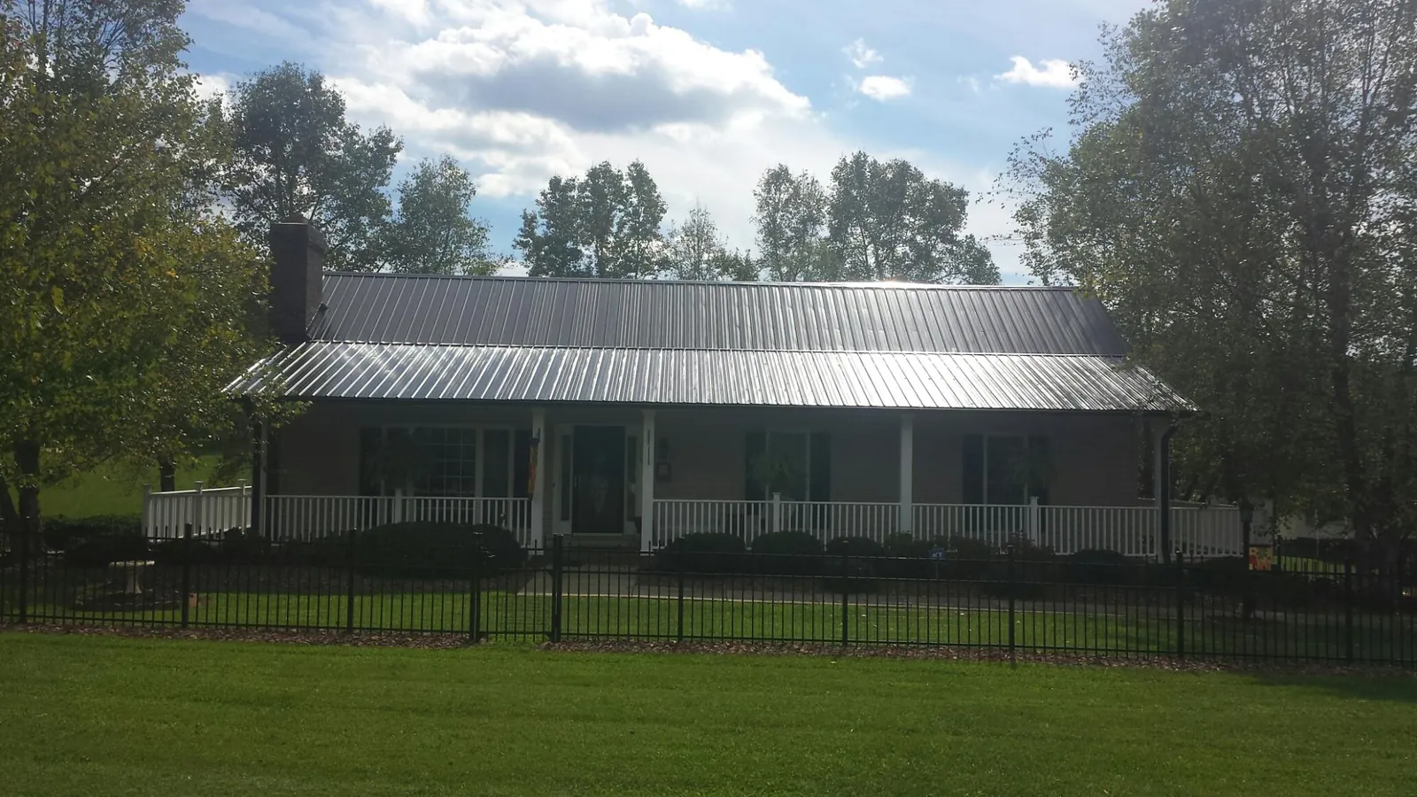 Gray metal roof on a brick ranch with a full width front porch — Gutter Guard Installation work by our crew in Brilliant